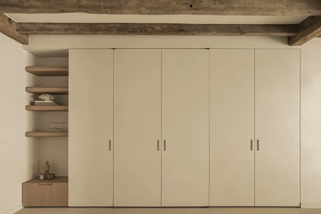 Gesloten kastenwand met crème deuren onder een eikenhouten balk, Totaalrenovatie in Loppem, interieur Laura Calleeuw