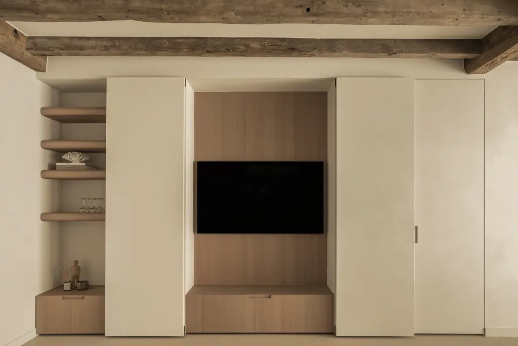 Kastenwand met verdoken televisie in eikenhouten nis en open planken onder een houten balk, Totaalrenovatie in Loppem, interieur Laura Calleeuw