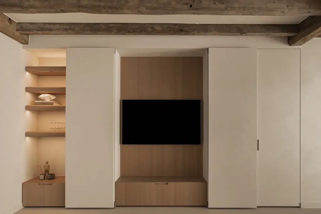 Kastenwand met verdoken televisie in eikenhouten nis en open planken onder een houten balk, Totaalrenovatie in Loppem, interieur Laura Calleeuw