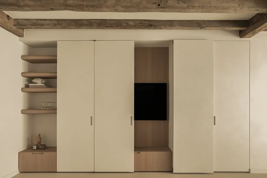 Kastenwand met verdoken televisie in eikenhouten nis en open planken onder een houten balk, Totaalrenovatie in Loppem, interieur Laura Calleeuw