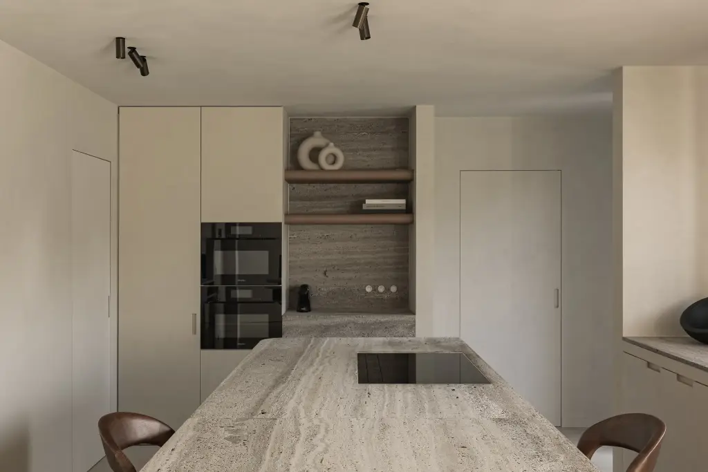 Keuken met eiland in travertijn, ovenkast en travertijn nis met houten planken, Totaalrenovatie in Loppem, interieur Laura Calleeuw