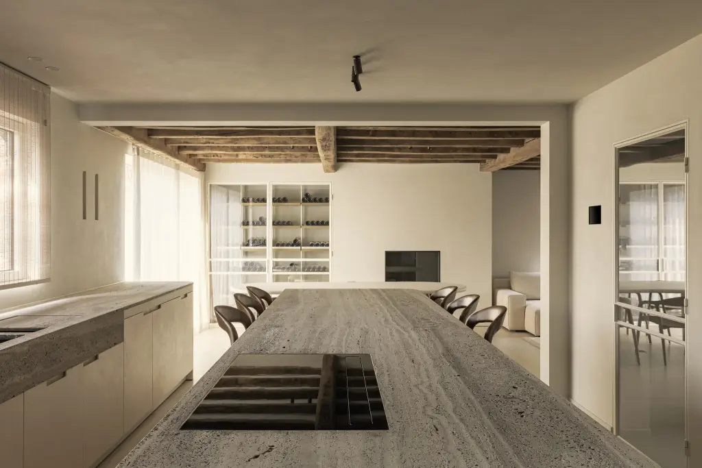 Lang travertijn eiland met kookplaat met zicht op eethoek en wijnkast, Totaalrenovatie in Loppem, interieur Laura Calleeuw