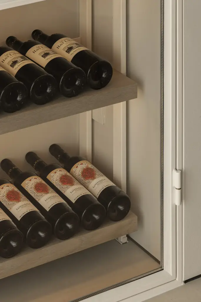 Detail van wijnflessen in schuine rekken, Totaalrenovatie in Loppem, interieur Laura Calleeuw