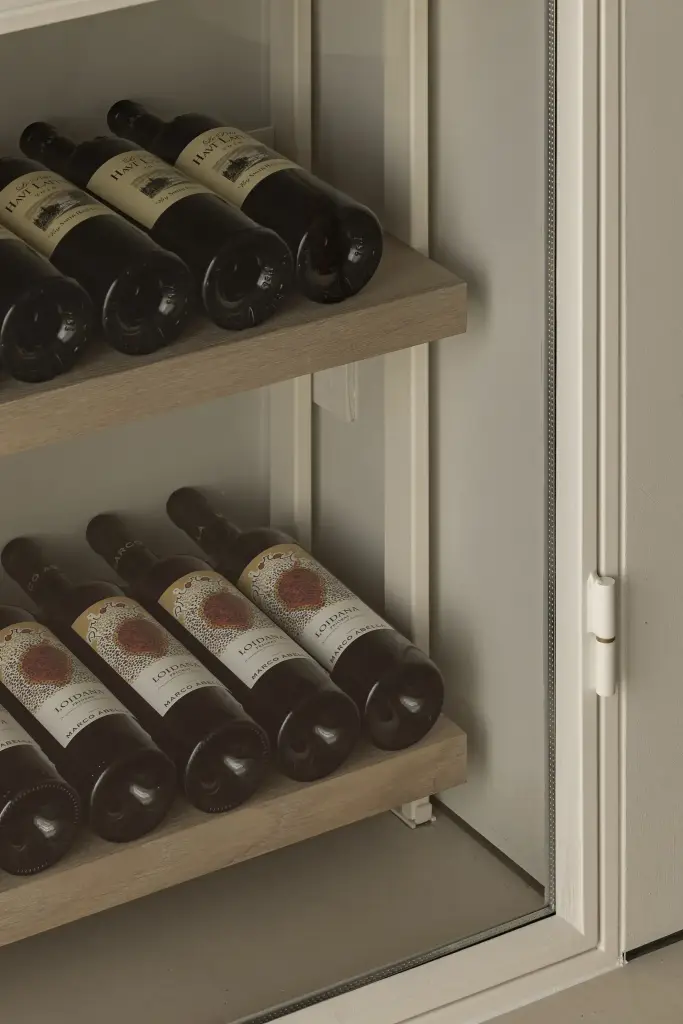 Detail van wijnflessen in schuine rekken, Totaalrenovatie in Loppem, interieur Laura Calleeuw