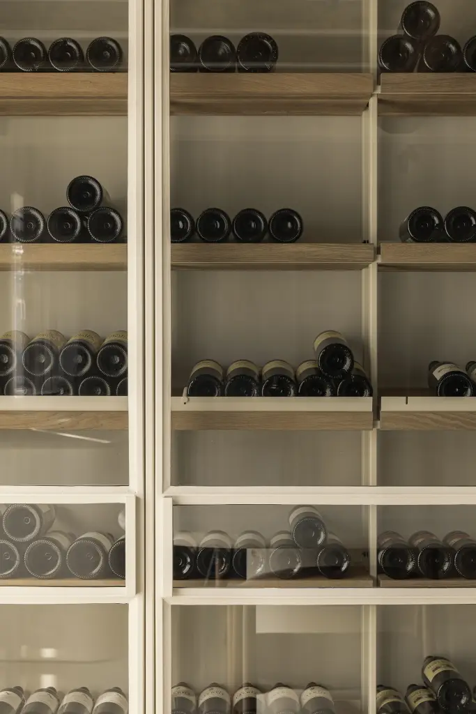 Wijnflessen in een kast met glazen deuren, Totaalrenovatie in Loppem, interieur Laura Calleeuw