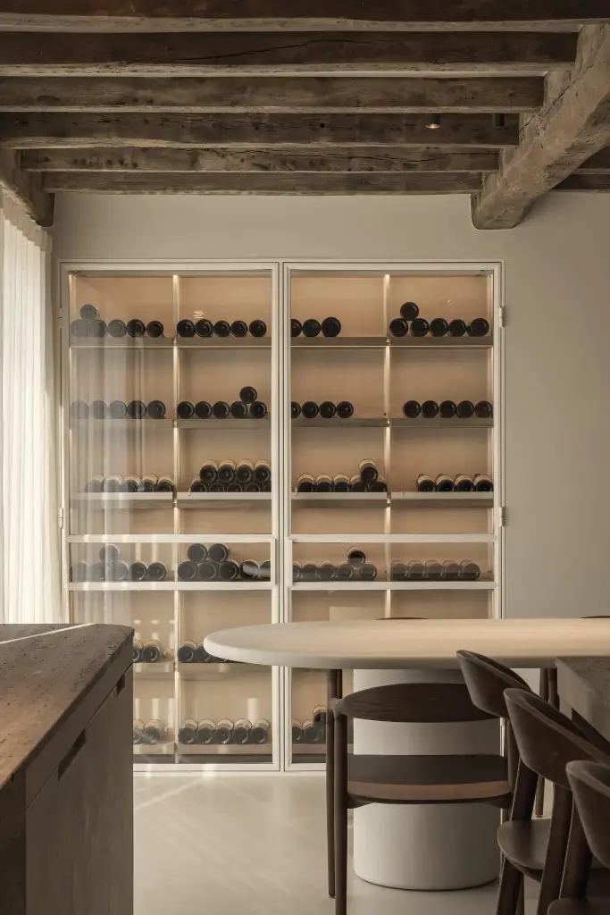 Glazen wijnkast achter de eethoek met ovale tafel, Totaalrenovatie in Loppem, interieur Laura Calleeuw