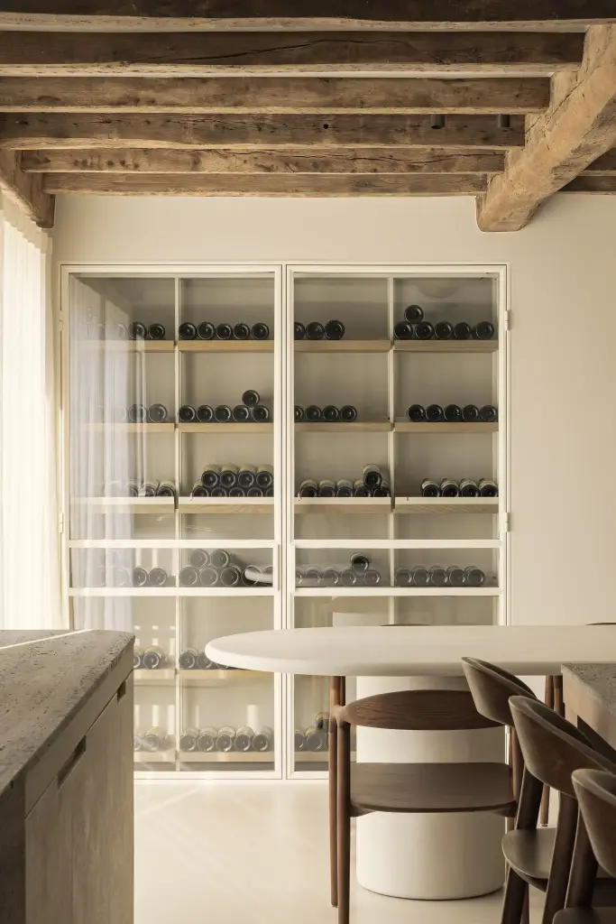 Glazen wijnkast achter de eethoek met ovale tafel, Totaalrenovatie in Loppem, interieur Laura Calleeuw