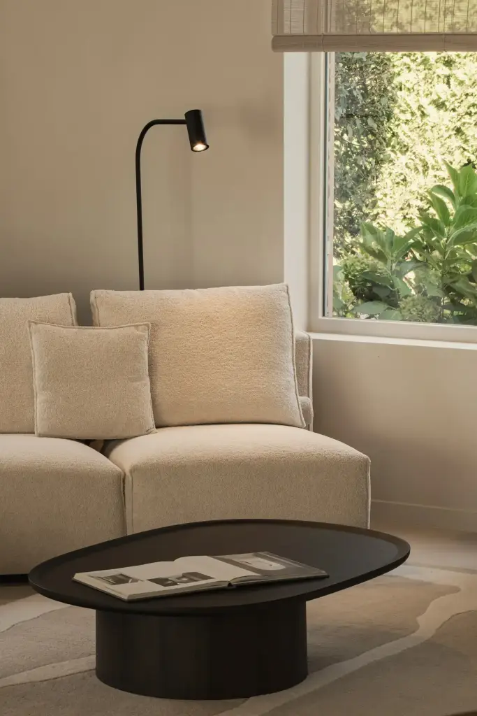 Zithoek met fauteuil, ronde zwarte salontafel en leeslamp voor het raam, Totaalrenovatie in Loppem, interieur Laura Calleeuw