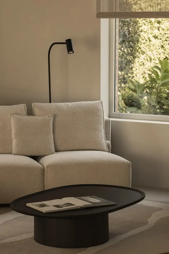 Zithoek met fauteuil, ronde zwarte salontafel en leeslamp voor het raam, Totaalrenovatie in Loppem, interieur Laura Calleeuw