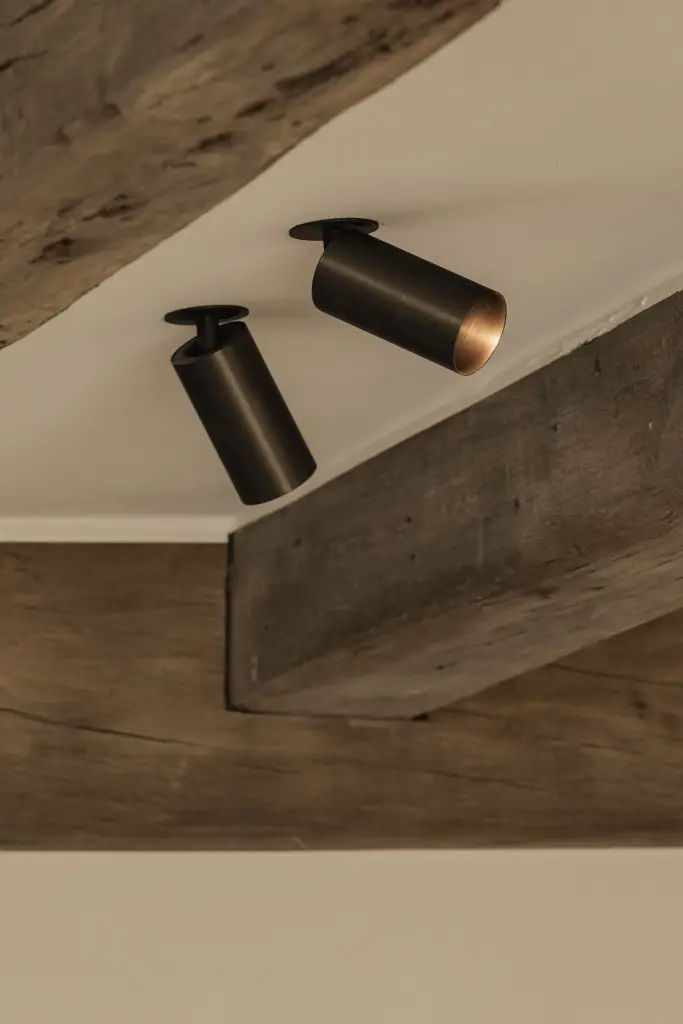 Zwarte opbouwspots tegen een eikenhouten balk, Totaalrenovatie in Loppem, interieur Laura Calleeuw