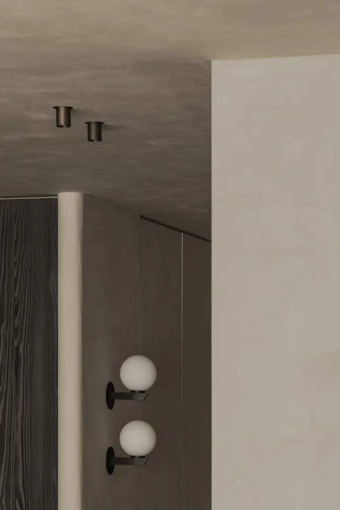 Bolvormige wandlampen en inbouwspots naast een microcement wand, Appartement in Knokke, interieur Laura Calleeuw