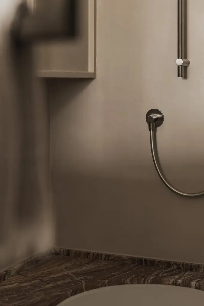 Handdouche en kraan tegen een microcement wand, Appartement in Knokke, interieur Laura Calleeuw