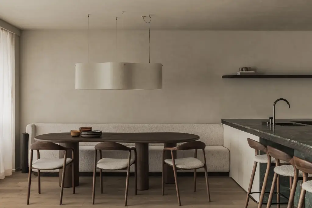 Eethoek met ovale tafel, houten stoelen, zitbank en ronde hanglamp, Appartement in Knokke, interieur Laura Calleeuw