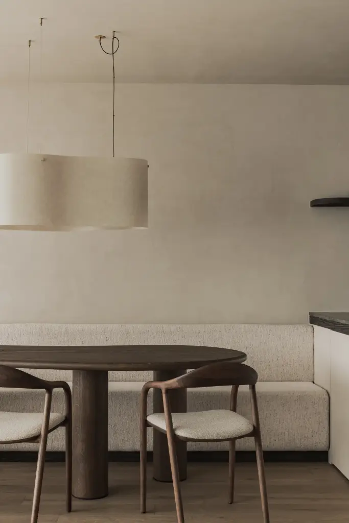 Eethoek met ovale tafel, houten stoelen, zitbank en ronde hanglamp, Appartement in Knokke, interieur Laura Calleeuw