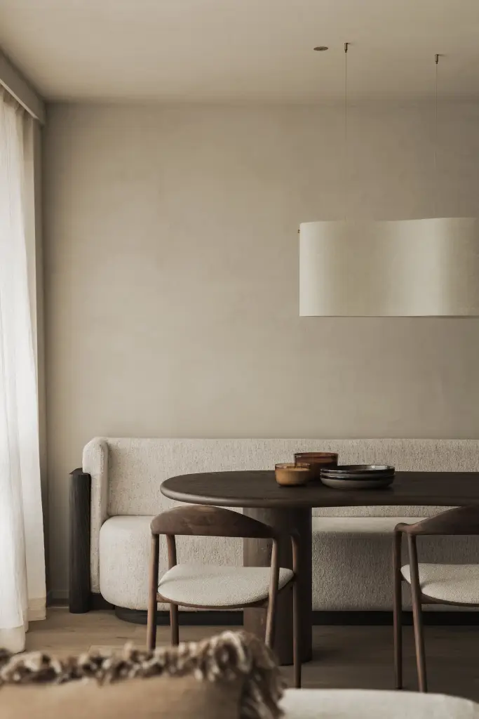 Eethoek met ovale tafel, houten stoelen, zitbank en ronde hanglamp, Appartement in Knokke, interieur Laura Calleeuw