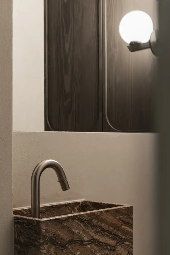 Onyx fonteintje met gebogen kraan en bolvormige wandlamp, Appartement in Knokke, interieur Laura Calleeuw