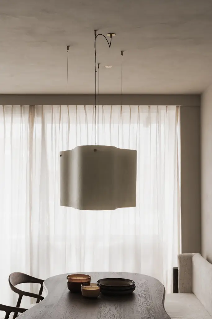 Hanglamp met stoffen kap boven de eettafel voor een gordijn, Appartement in Knokke, interieur Laura Calleeuw