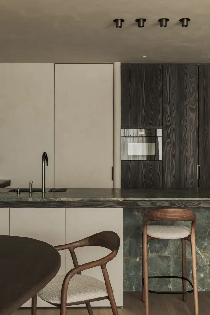 Keuken met eiland in groen marmer, houten barkrukken en ovenkast in donker eiken, Appartement in Knokke, interieur Laura Calleeuw