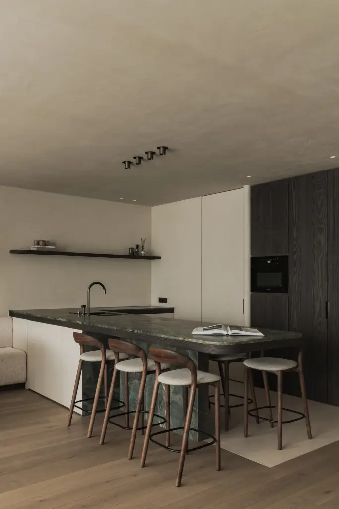 Keuken met eiland in groen marmer, houten barkrukken en ovenkast in donker eiken, Appartement in Knokke, interieur Laura Calleeuw