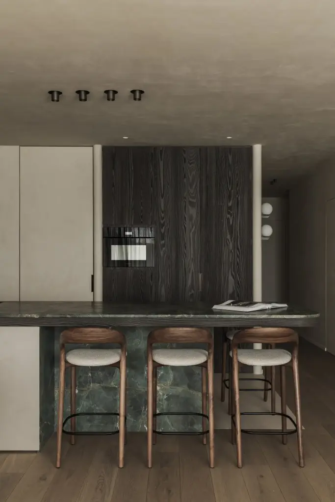 Keuken met eiland in groen marmer, houten barkrukken en ovenkast in donker eiken, Appartement in Knokke, interieur Laura Calleeuw