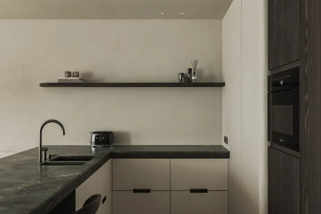 Keuken met groen marmeren werkblad, zwarte wandplank en kraan, Appartement in Knokke, interieur Laura Calleeuw