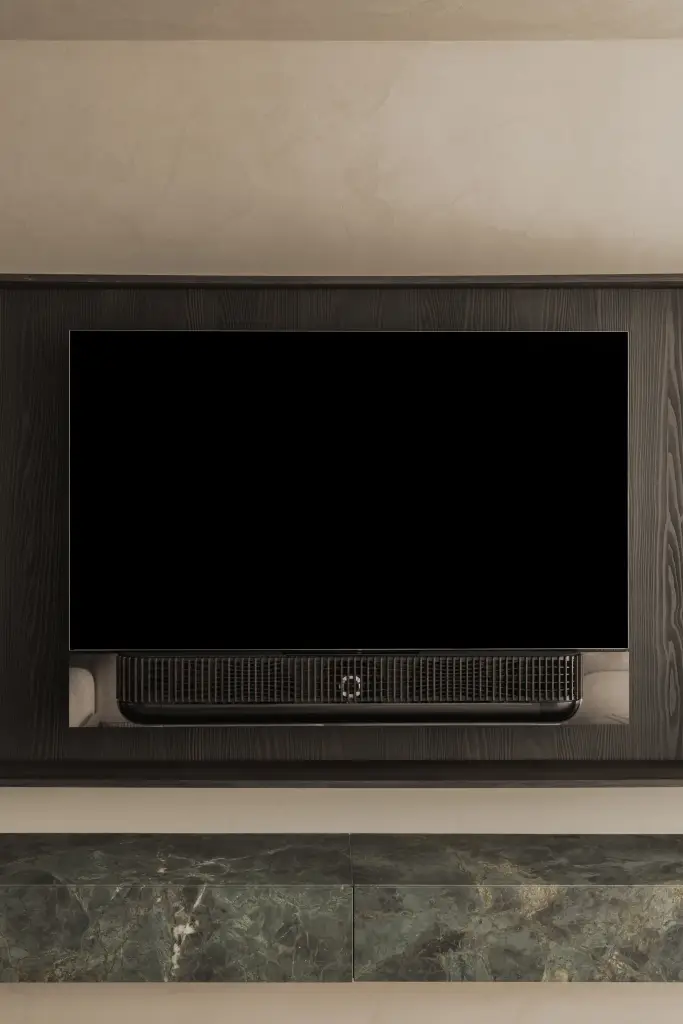 Televisie in een afgeronde nis van donker eiken boven een marmeren plank, Appartement in Knokke, interieur Laura Calleeuw