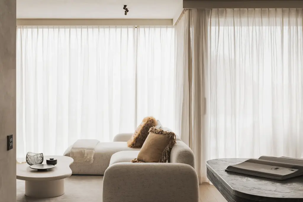 Zithoek met ronde zetel, organische bijzettafel en gordijnen in voile, Appartement in Knokke, interieur Laura Calleeuw