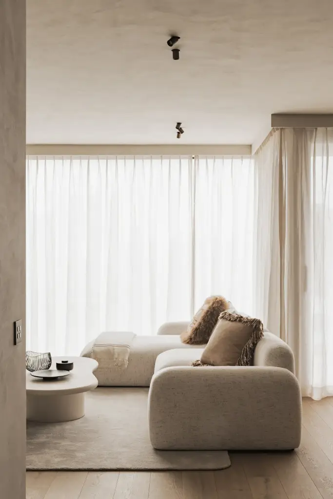 Zithoek met ronde zetel, organische bijzettafel en gordijnen in voile, Appartement in Knokke, interieur Laura Calleeuw