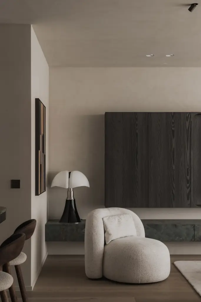 Zithoek met bouclé fauteuil, vloerlamp en televisiewand in donker eiken, Appartement in Knokke, interieur Laura Calleeuw